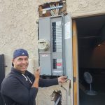 New 200-amp meter-main combo installed; customer pointing to main breaker — exterior wall