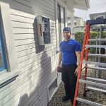 Electrician beside exterior panel upgrade with ladder — Los Angeles home